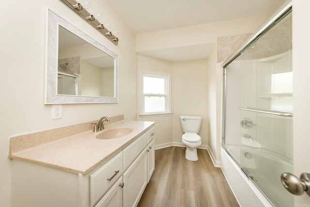 full bathroom featuring bath / shower combo with glass door, vanity, toilet, and wood-type flooring