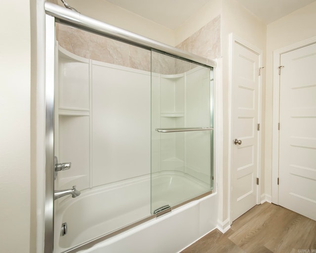 bathroom featuring wood-type flooring and shower / bath combination with glass door