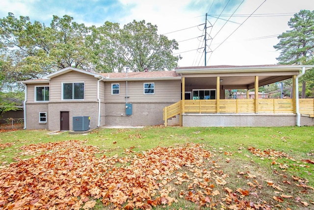 back of house with central AC unit and a yard