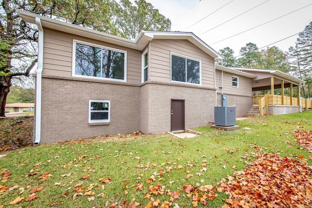 rear view of house with central air condition unit and a yard