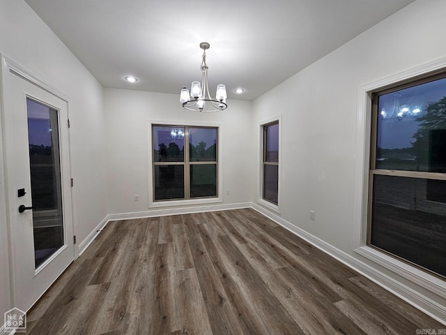 unfurnished dining area with dark hardwood / wood-style floors and a chandelier