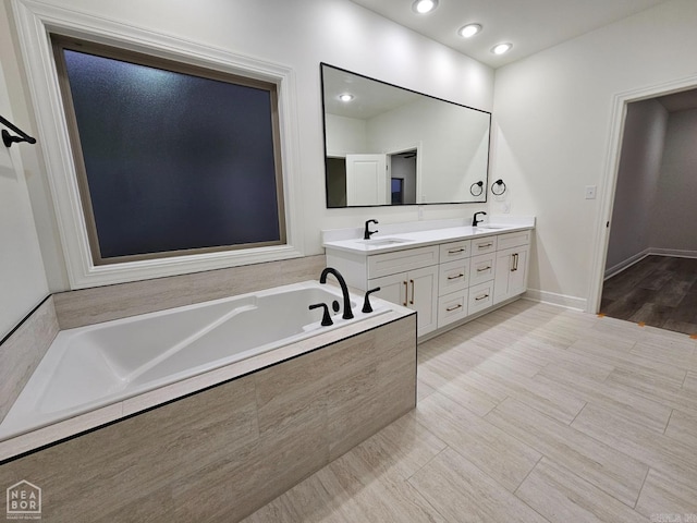 bathroom featuring tiled bath, hardwood / wood-style floors, and vanity