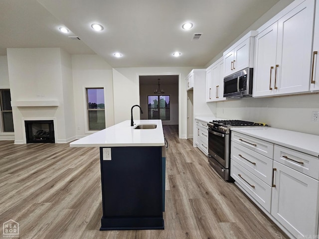 kitchen with white cabinetry, a center island with sink, stainless steel appliances, and sink