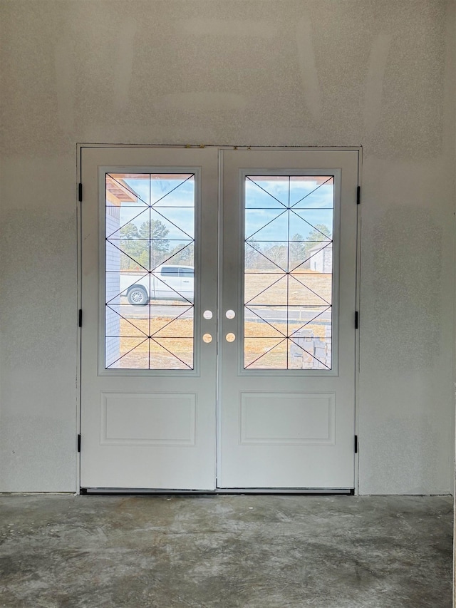 doorway to outside featuring concrete floors, a healthy amount of sunlight, and french doors