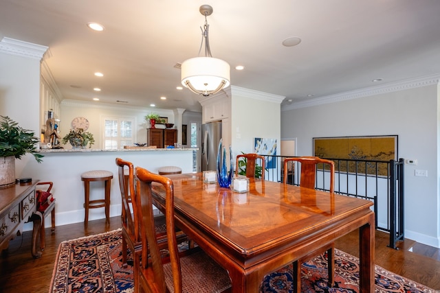 dining space featuring decorative columns, dark hardwood / wood-style floors, and ornamental molding