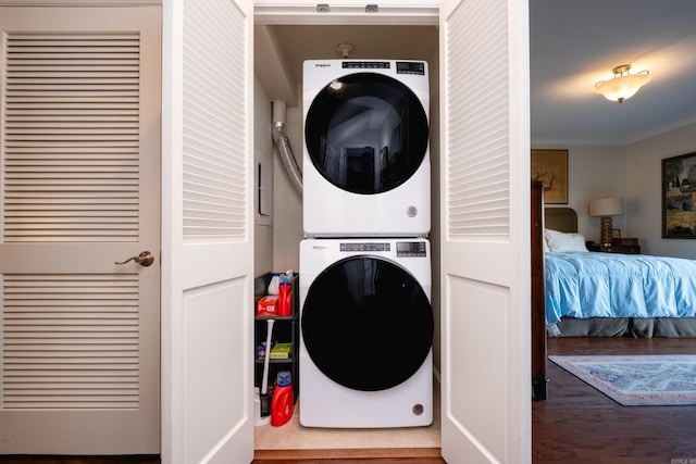 laundry area featuring stacked washer and clothes dryer and crown molding