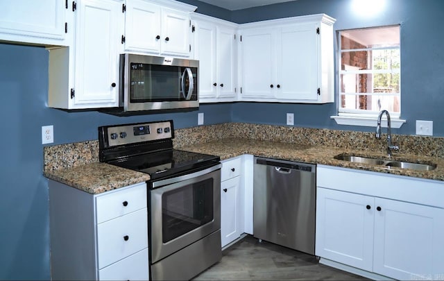 kitchen with white cabinetry, sink, appliances with stainless steel finishes, dark stone counters, and dark wood-type flooring