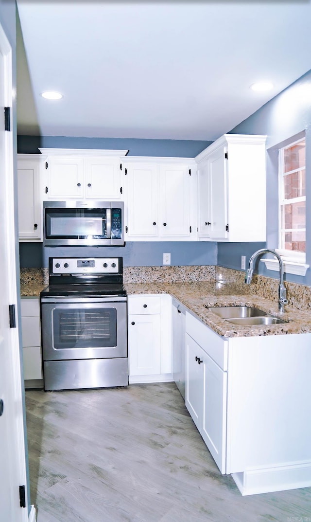 200 Pine Forest Dr Apt C2, Maumelle, AR 72113 - kitchen with a sink, appliances with stainless steel finishes, white cabinets, light wood-style floors, and light stone counters
