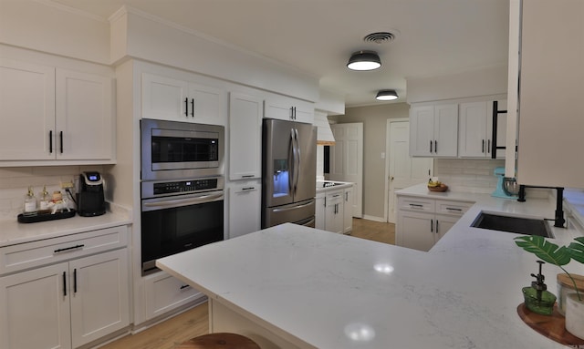 2006 S Prairie St, Stuttgart, AR 72160 - kitchen with stainless steel appliances, a sink, backsplash, white cabinets, and a peninsula