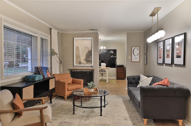 living room featuring a fireplace, light hardwood / wood-style floors, a chandelier, and crown molding