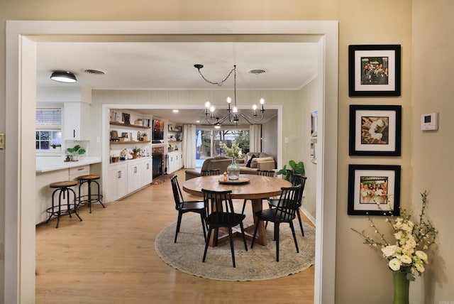 2006 S Prairie St, Stuttgart, AR 72160 - dining area with crown molding, light wood-type flooring, a chandelier, and baseboards