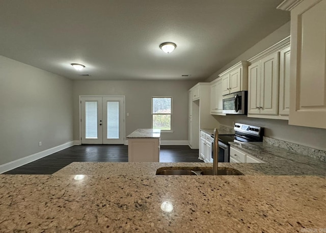 kitchen with french doors, light stone counters, appliances with stainless steel finishes, sink, and dark wood-type flooring