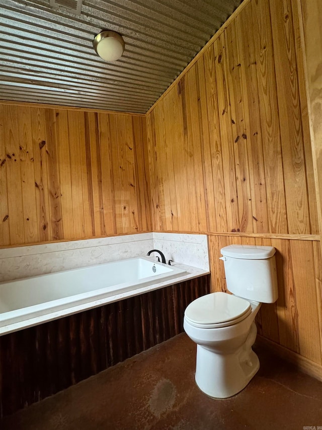 bathroom with wood walls, a tub to relax in, and toilet