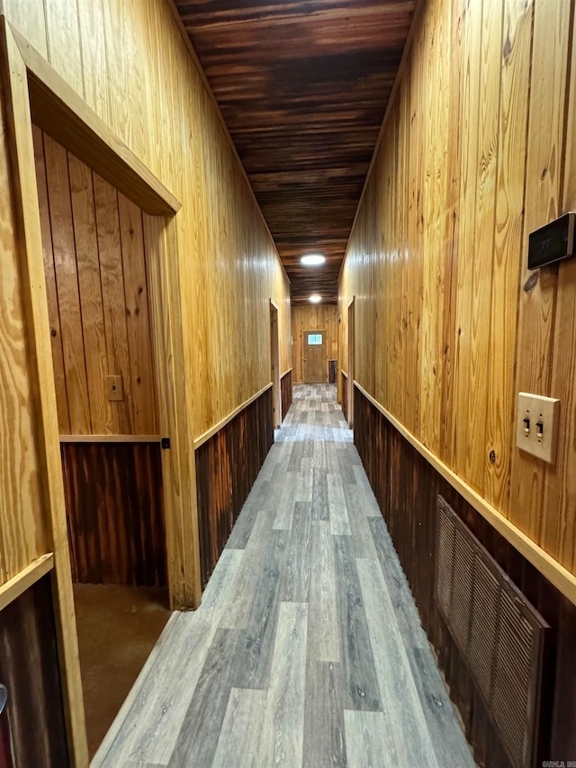 hall with hardwood / wood-style floors, wooden walls, and wood ceiling