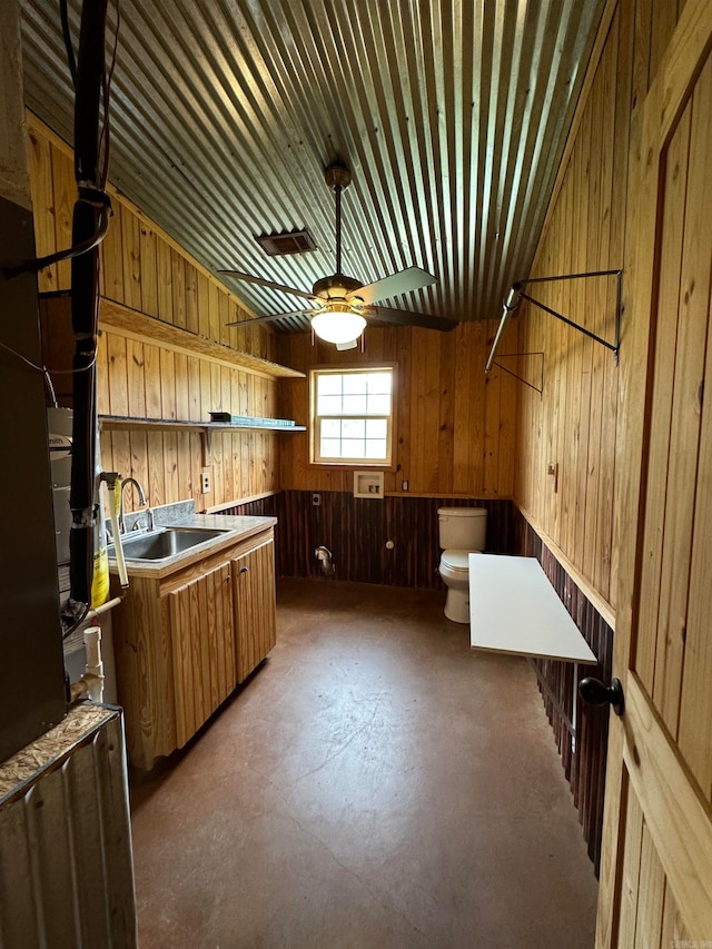 kitchen featuring concrete flooring, wood walls, and sink