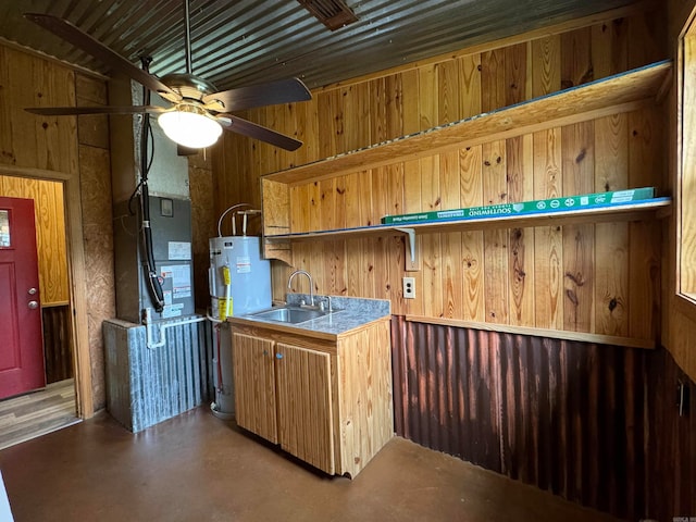 kitchen with concrete floors, water heater, wood walls, sink, and ceiling fan