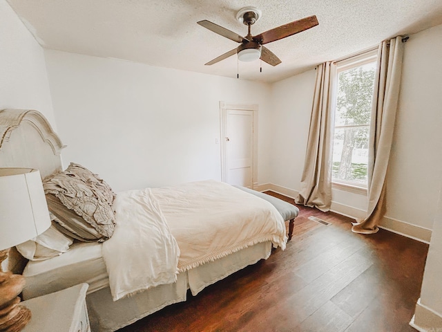 bedroom featuring ceiling fan, a textured ceiling, and dark hardwood / wood-style flooring