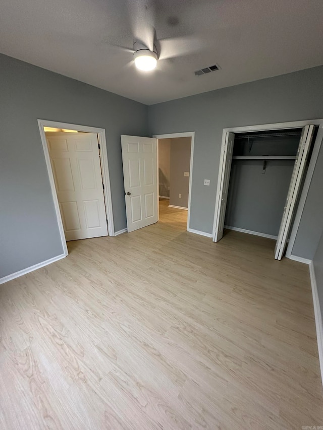 unfurnished bedroom featuring a closet, a textured ceiling, ceiling fan, and light hardwood / wood-style flooring