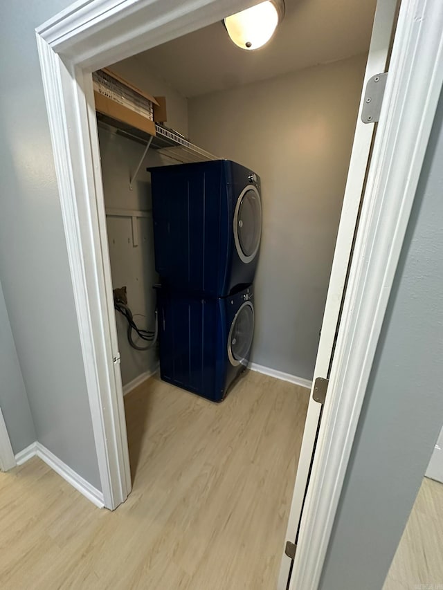 washroom with light wood-type flooring and stacked washer / drying machine