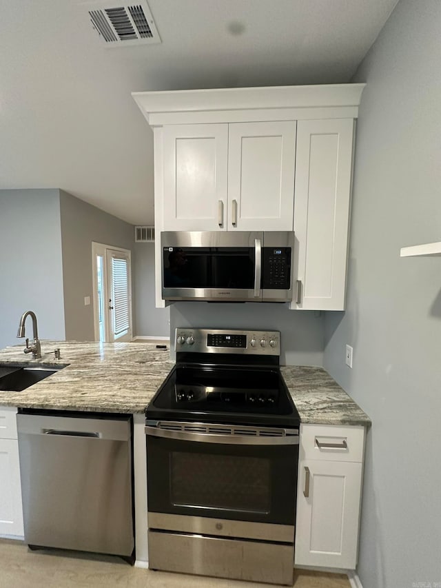 kitchen with light stone countertops, white cabinetry, sink, and appliances with stainless steel finishes