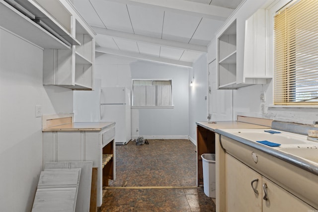 kitchen featuring white fridge and vaulted ceiling with beams