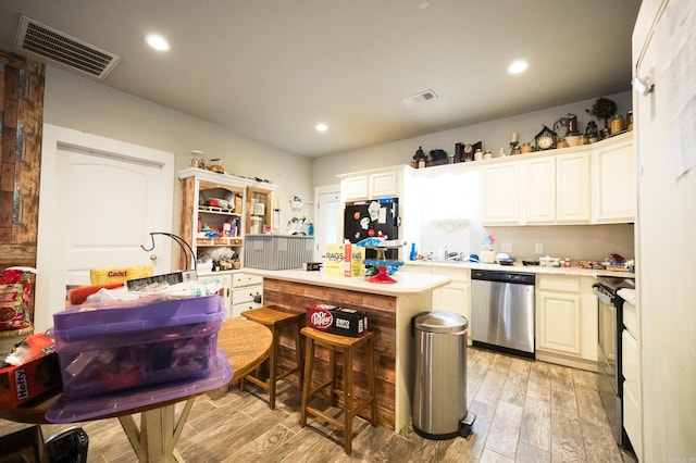 kitchen with black appliances, a center island, white cabinets, and light hardwood / wood-style flooring