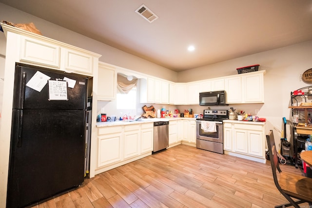 kitchen with white cabinets, light hardwood / wood-style flooring, black appliances, and sink