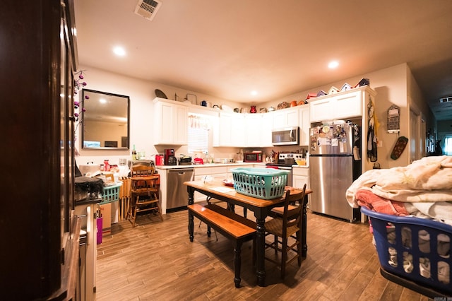 kitchen with white cabinets, light wood-type flooring, and appliances with stainless steel finishes