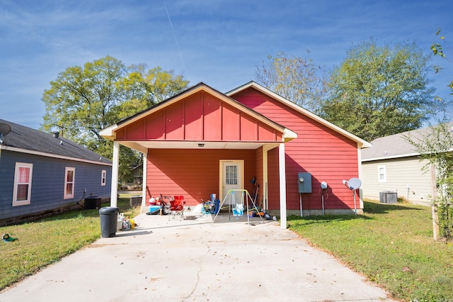 rear view of property with central AC unit and a lawn