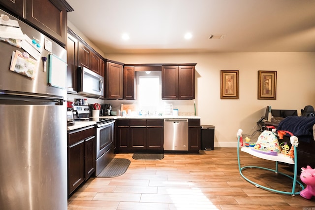 kitchen featuring dark brown cabinetry, appliances with stainless steel finishes, light hardwood / wood-style floors, and sink