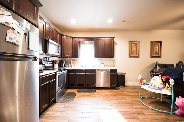 kitchen featuring dark brown cabinetry, light hardwood / wood-style floors, and stainless steel appliances