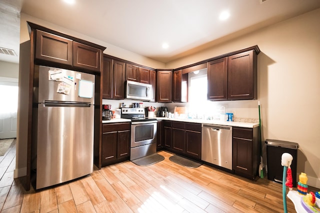 kitchen with stainless steel appliances, light hardwood / wood-style floors, sink, and dark brown cabinetry