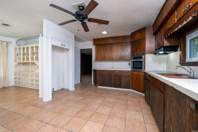 kitchen with dark brown cabinetry, sink, light tile patterned floors, backsplash, and oven