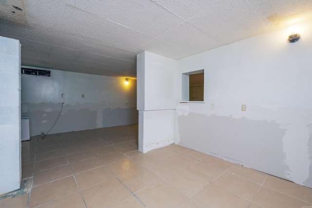 basement with a textured ceiling and light tile patterned floors