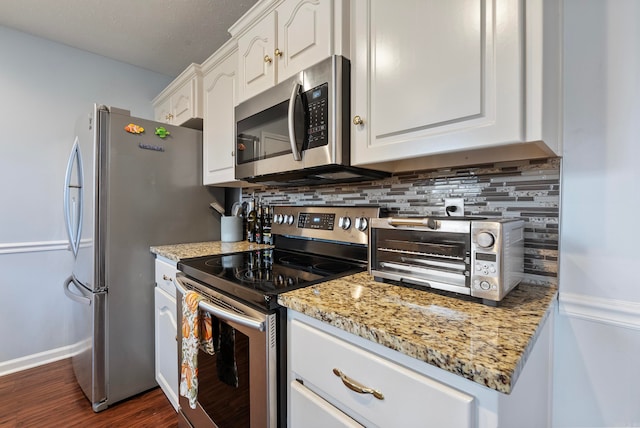 kitchen with dark wood-type flooring, tasteful backsplash, light stone countertops, white cabinetry, and appliances with stainless steel finishes