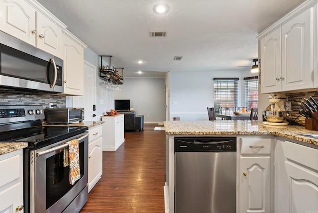 kitchen with white cabinetry, decorative backsplash, stainless steel appliances, and dark hardwood / wood-style floors