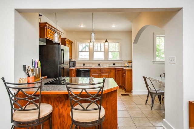 kitchen with a healthy amount of sunlight, kitchen peninsula, black appliances, and a breakfast bar area