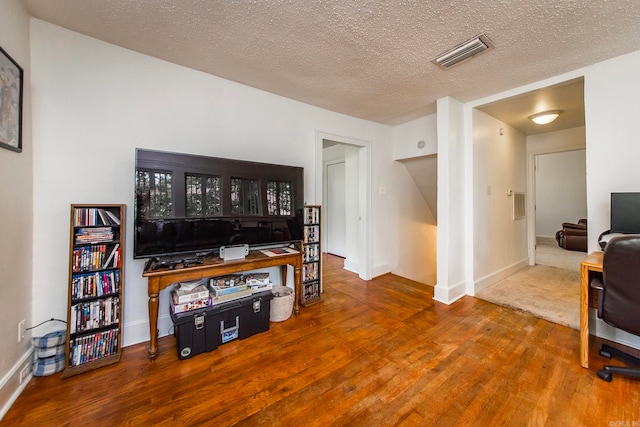 living room featuring wood-type flooring and a textured ceiling