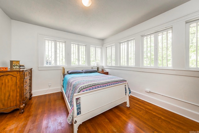 bedroom with dark hardwood / wood-style floors and a textured ceiling