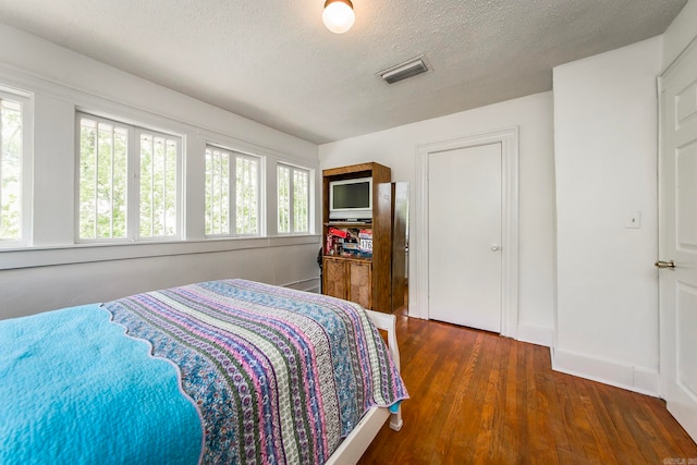 bedroom featuring a textured ceiling and dark hardwood / wood-style flooring