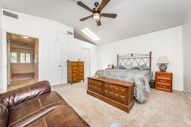 carpeted bedroom with ceiling fan and vaulted ceiling with skylight