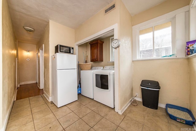 laundry area with cabinets, separate washer and dryer, and light tile patterned floors