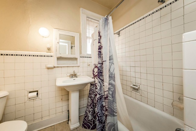 full bathroom featuring tile patterned flooring, sink, shower / bathtub combination with curtain, toilet, and tile walls