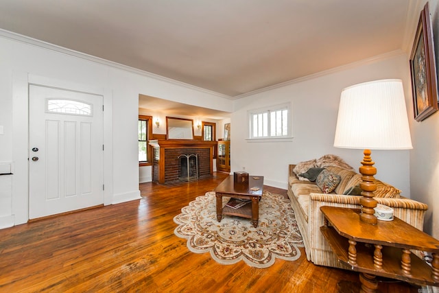 living room featuring ornamental molding, a brick fireplace, and dark hardwood / wood-style flooring