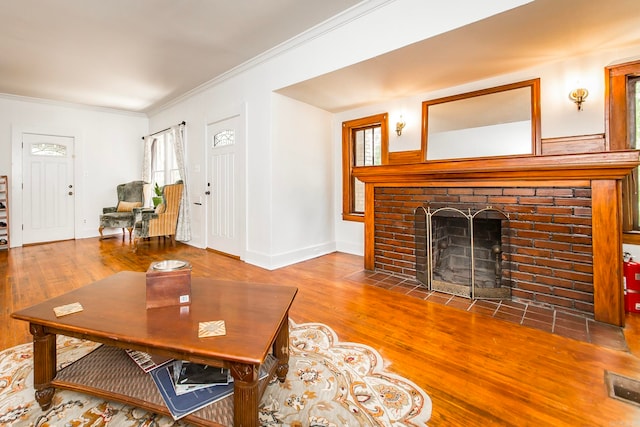 living room featuring a brick fireplace, wood-type flooring, and ornamental molding