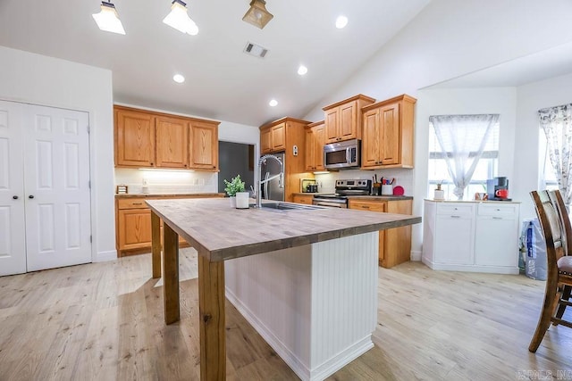 169 Whispering Oak Cir, El Dorado, AR 71730 - kitchen featuring stainless steel appliances, wood counters, a sink, vaulted ceiling, and a center island with sink