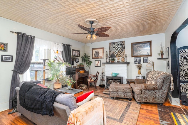 living room featuring hardwood / wood-style flooring, ceiling fan, and a fireplace