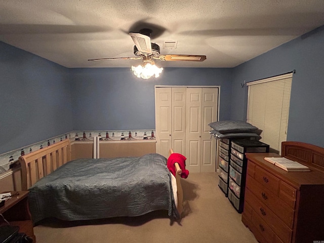 carpeted bedroom with a closet, a textured ceiling, and ceiling fan