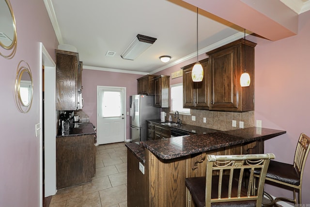 kitchen featuring a kitchen bar, kitchen peninsula, decorative light fixtures, and stainless steel fridge