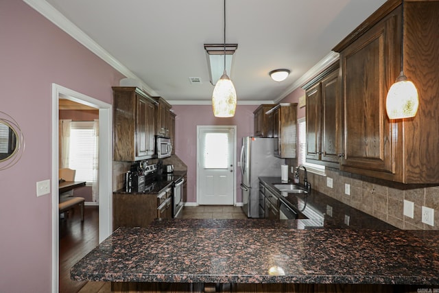 kitchen featuring stainless steel appliances, hardwood / wood-style floors, kitchen peninsula, sink, and decorative light fixtures